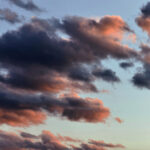 暗い雲のあいだから柔らかな光が差し込む、静かな夕空の風景