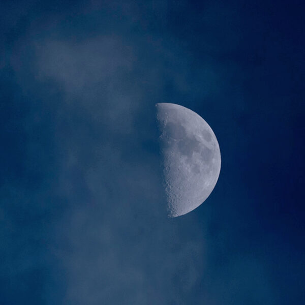 雲の間から半月が浮かぶ夜空の風景