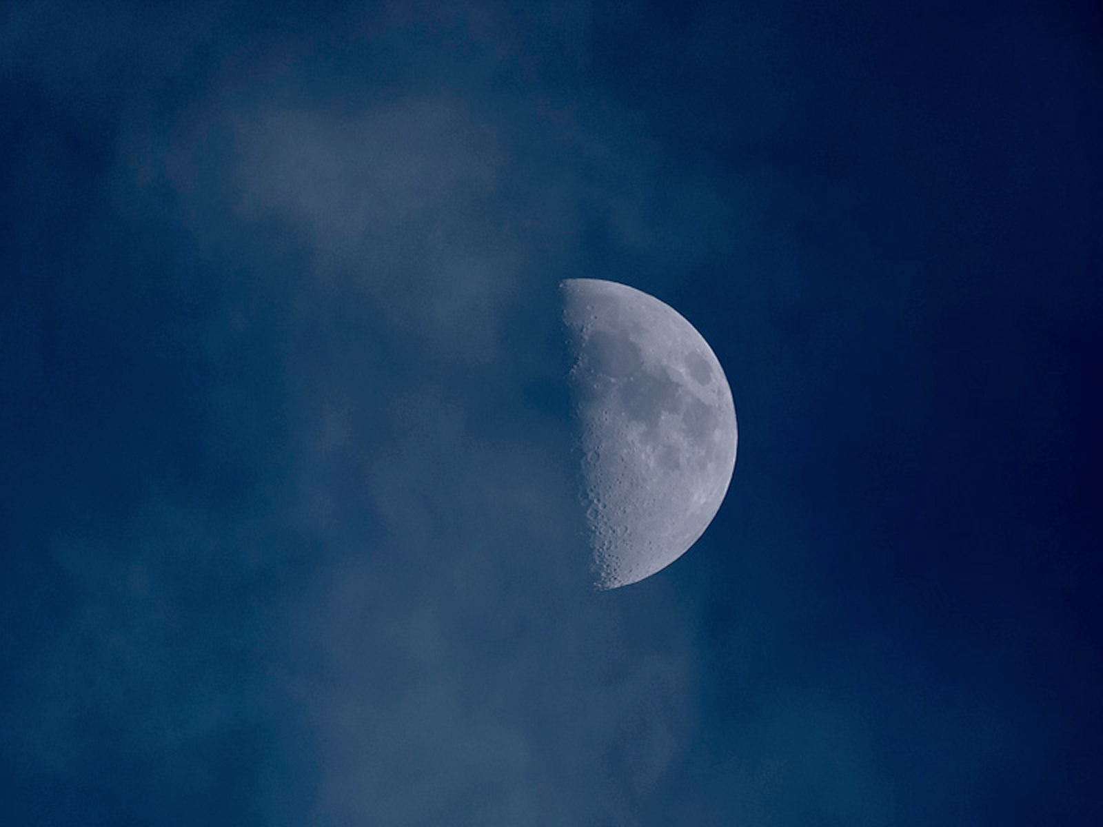 雲の間から半月が浮かぶ夜空の風景
