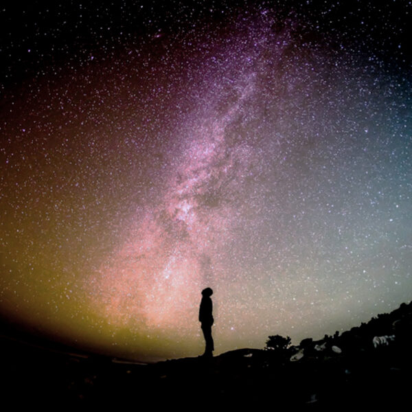 星空を見上げる人のシルエットと、広がる夜空の風景